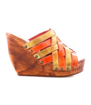 The Bed Stu Josie II is a brown wooden wedge sandal with orange and tan hand-woven leather straps and metal studs, shown on a white background.