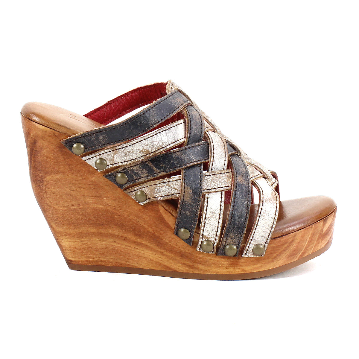 The Josie II by Bed Stu is a wooden wedge sandal with hand-woven black and metallic silver leather straps, finished with decorative metal studs for added style.