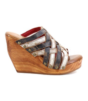 The Josie II by Bed Stu is a wooden wedge sandal with hand-woven black and metallic silver leather straps, finished with decorative metal studs for added style.