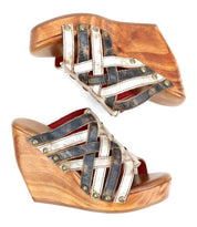 The Josie II by Bed Stu: wooden wedge sandals featuring hand-woven black and white leather crisscross straps with brass stud accents, shown from the side.