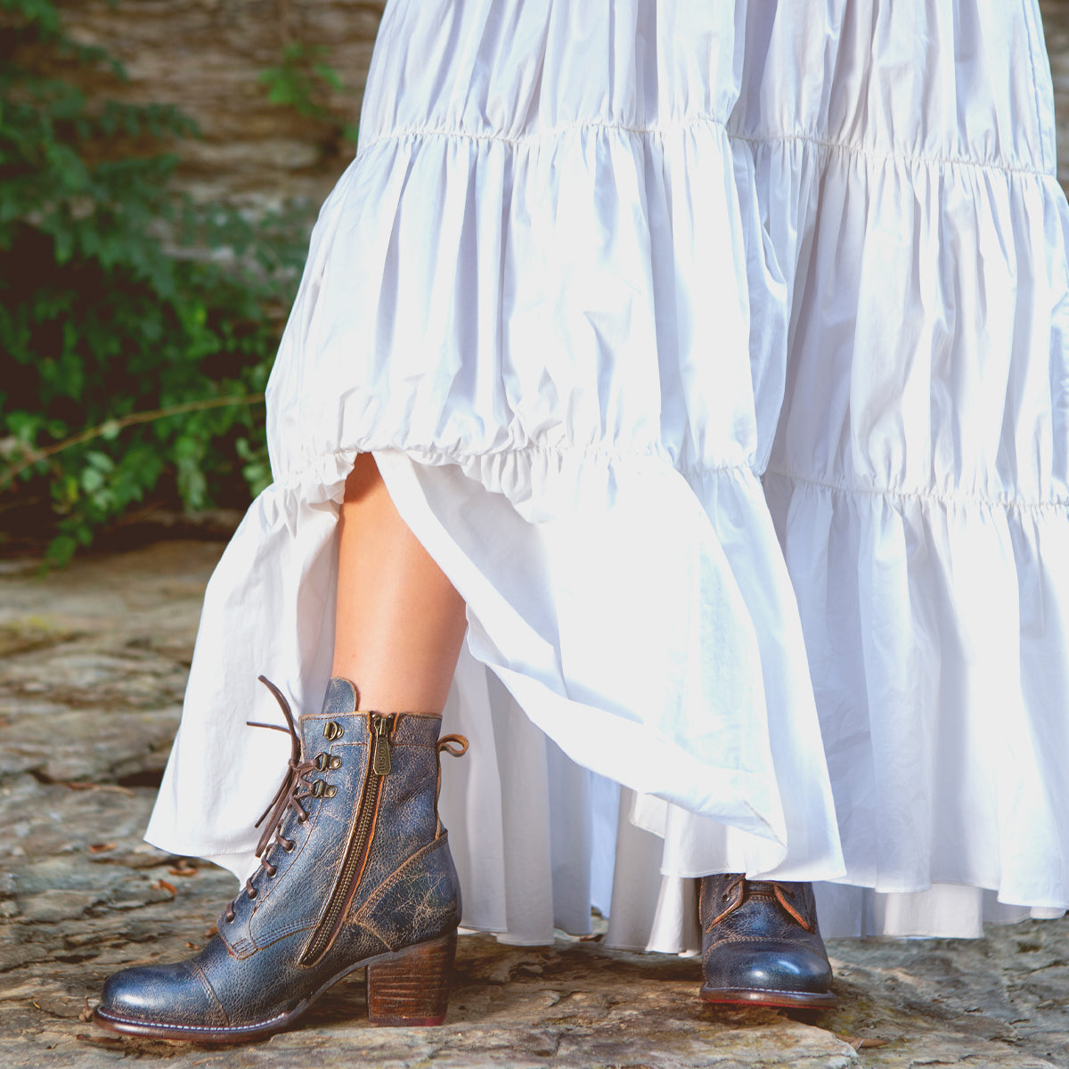 A woman wearing a white dress and Bed Stu Judgement boots.