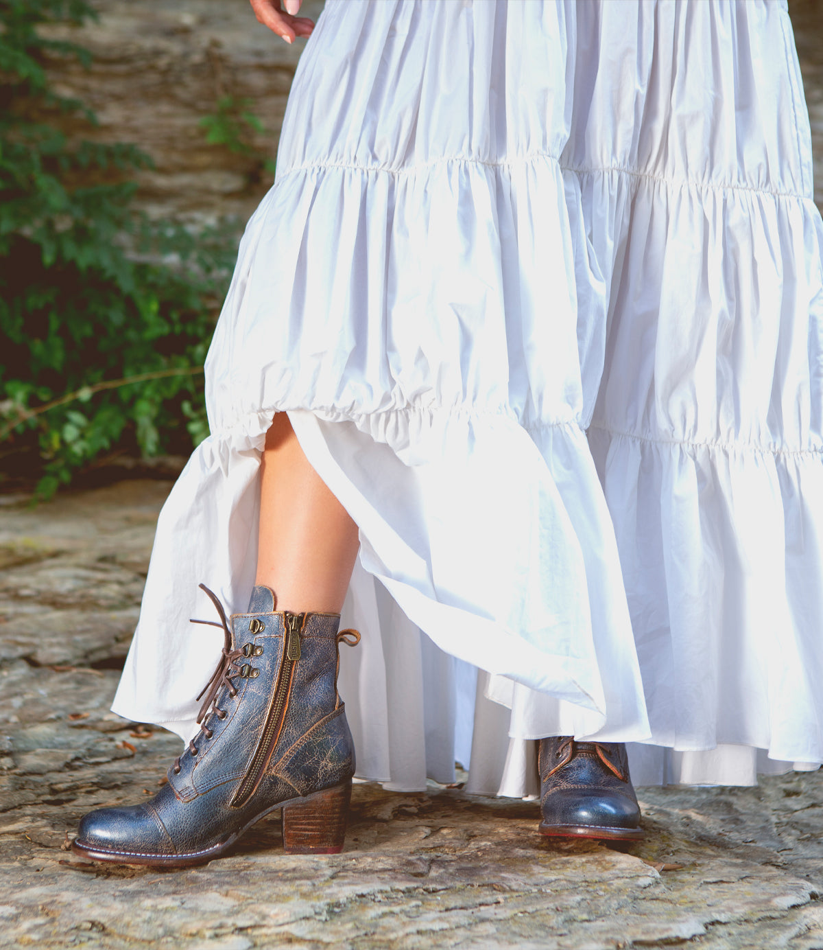 A woman wearing a white dress and Bed Stu Judgement boots.
