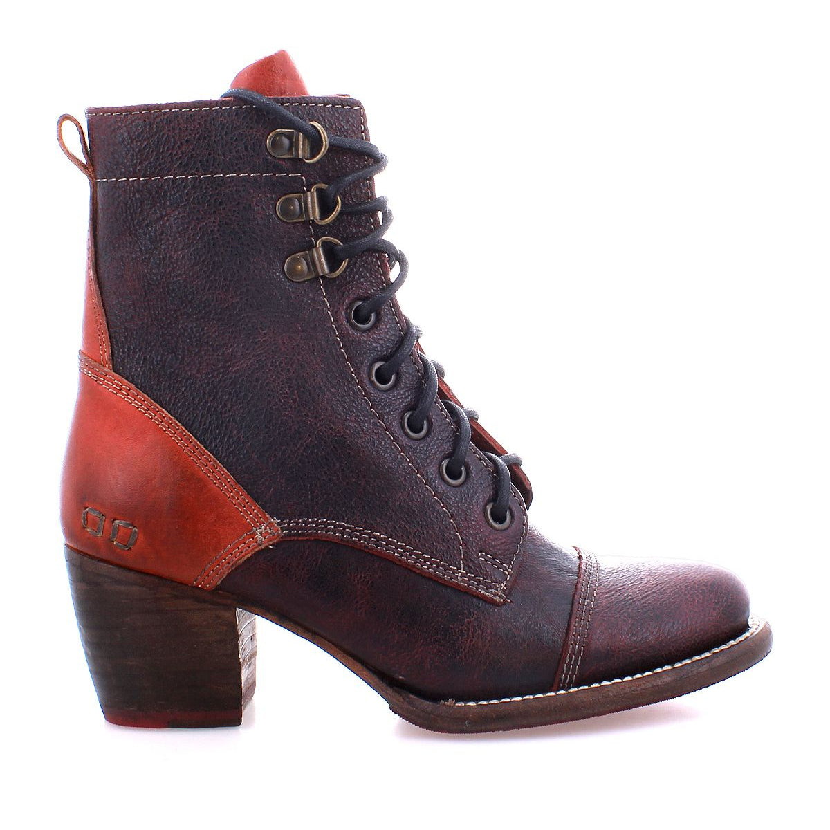 The Bed Stu Judgement boot is a brown leather ankle boot with an 8-eye lace-up design, featuring a 2-inch wooden block heel and eye-catching red accents.