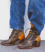 Person wearing blue jeans and Bed Stu's Judgement brown leather 8-eye lace-up boots with heels, standing against a white background.