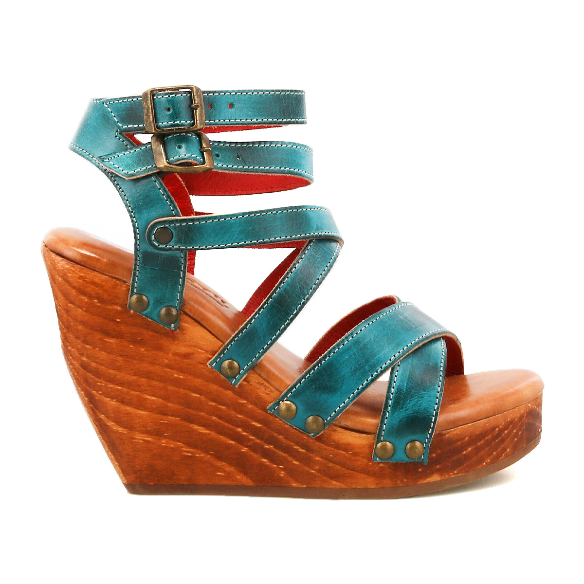 The Bed Stu Juliana II wedge sandal features a teal strappy upper, wooden platform sole, buckle closures, and metal rivet accents, displayed in a side view against a white background.