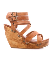 The Juliana II by Bed Stu is a brown wedge sandal with a strappy, studded upper, two buckles, wooden heel, and rivet details.