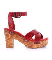The Kalah by Bed Stu is a red leather high-heeled sandal featuring a wooden sole, an ankle strap, metallic studs, and a stylish platform heel.