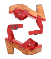 The Kalah platform sandals by Bed Stu, featuring red leather with wooden block heels and ankle straps adorned with metal rivet details, are crafted from sustainably sourced materials. These sandals offer an eco-conscious design while maintaining a stylish look.