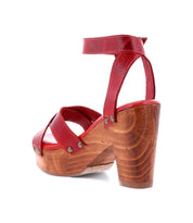 Elevate your style with the Kalah high-heeled sandal by Bed Stu. This red beauty boasts a wooden platform heel and an ankle strap embellished with metal studs, crafted from sustainably sourced materials for a look that's as responsible as it is chic.