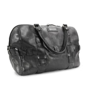 A black leather travel duffle bag with double handles and woven detailing on the sides, handcrafted from premium vegetable tanned leather, the Keg from Bed Stu.