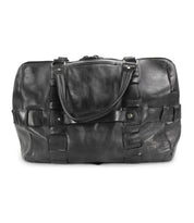 A handcrafted black leather travel duffle bag with two handles and a shoulder strap, featuring decorative buckles and a zippered top, made from premium vegetable tanned leather, the Keg by Bed Stu.
