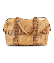 A large, tan leather travel duffle bag called the Keg by Bed Stu with multiple straps and buckles is shown against a white background, showcasing its handcrafted quality and functional design.
