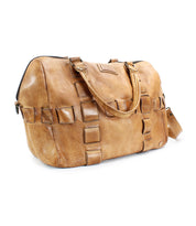 A handcrafted tan leather travel duffle bag with square patch detailing, featuring a short handle and an adjustable shoulder strap from Bed Stu, called Keg.