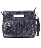 The Keiki by Bed Stu is a purple textured leather crossbody bag featuring front woven panels, metal studs, and a detachable, adjustable strap.