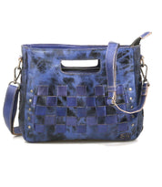 The Keiki by Bed Stu is a compact blue leather handbag with woven checkerboard panels, metal studs, a detachable shoulder strap for crossbody use, and a chic cutout handle.