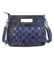 The Keiki by Bed Stu is a blue leather crossbody bag with woven square panels, metal studs, a cutout handle, and a detachable shoulder strap—an ideal compact accessory for everyday style.