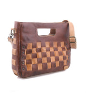 The Bed Stu Keiki is a brown leather woven checkerboard bag with an adjustable strap, built-in handle, and metal rivet details. This compact crossbody makes a graphic statement and elevates any outfit.