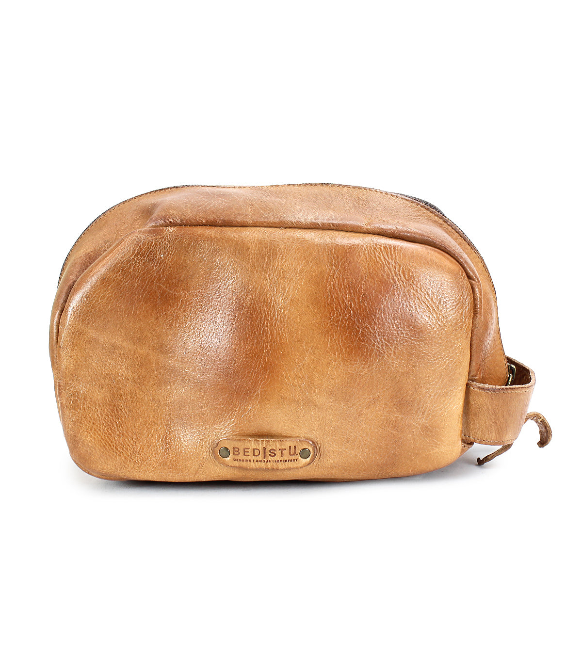 Tan leather dopp kit with a zip closure and a small handle on the side, featuring a metal plate label that reads "Bed Stu." Crafted from vegetable tanned leather, this luxurious Kip bag is perfect for your travel essentials.