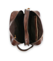 Top view of a brown leather dopp kit with its main compartment and inner pocket open, revealing a dark interior. The Kip by Bed Stu, crafted from vegetable-tanned leather, has a single handle, making it perfect for carrying travel essentials.