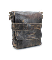 A weathered brown handmade leather messenger bag with a flap closure and decorative stitching, featuring a worn label on the front and an organic cotton-lined interior, called Kure by Bed Stu.