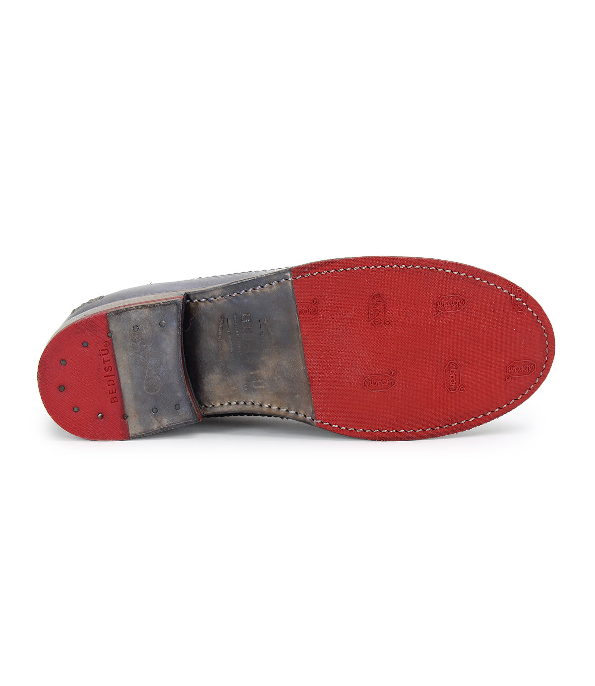 The image showcases the bottom of a Bed Stu Lita K - Archived shoe, featuring a red sole and brown heel with decorative stitching hinting at a derby shape. "Fregius" is elegantly printed on the heel.