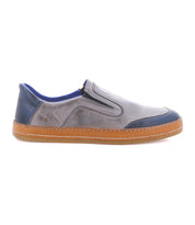 The Bed Stu Lanius is a gray and blue slip-on shoe with a brown rubber sole, shown in side profile, featuring color blocking for a fresh spin on a classic silhouette.
