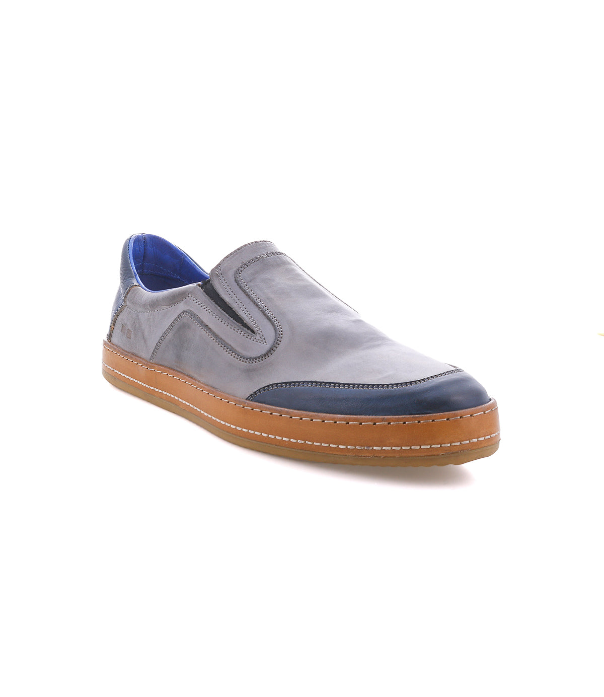 The Bed Stu Lanius features a gray slip-on design with a timeless silhouette, a brown sole, blue inner lining, and dark toe cap, showcasing modern color blocking on a white background.