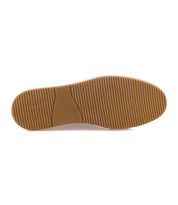 The photo displays the bottom view of the Bed Stu Lanius slip-on, featuring a light brown rubber sole with horizontal grooves and a smooth arch, showcasing its timeless silhouette.