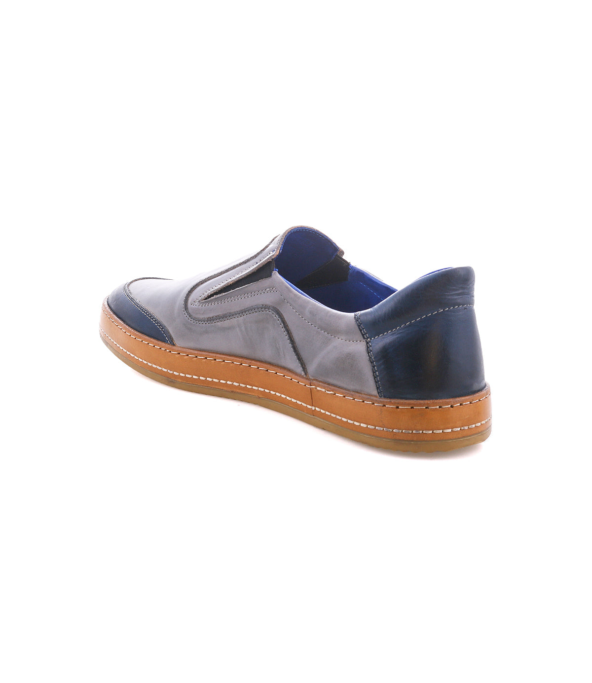 The Bed Stu Lanius is a slip-on shoe with a timeless silhouette, blue and gray leather color blocking, elastic side panels, and a tan rubber sole, displayed on a white background.
