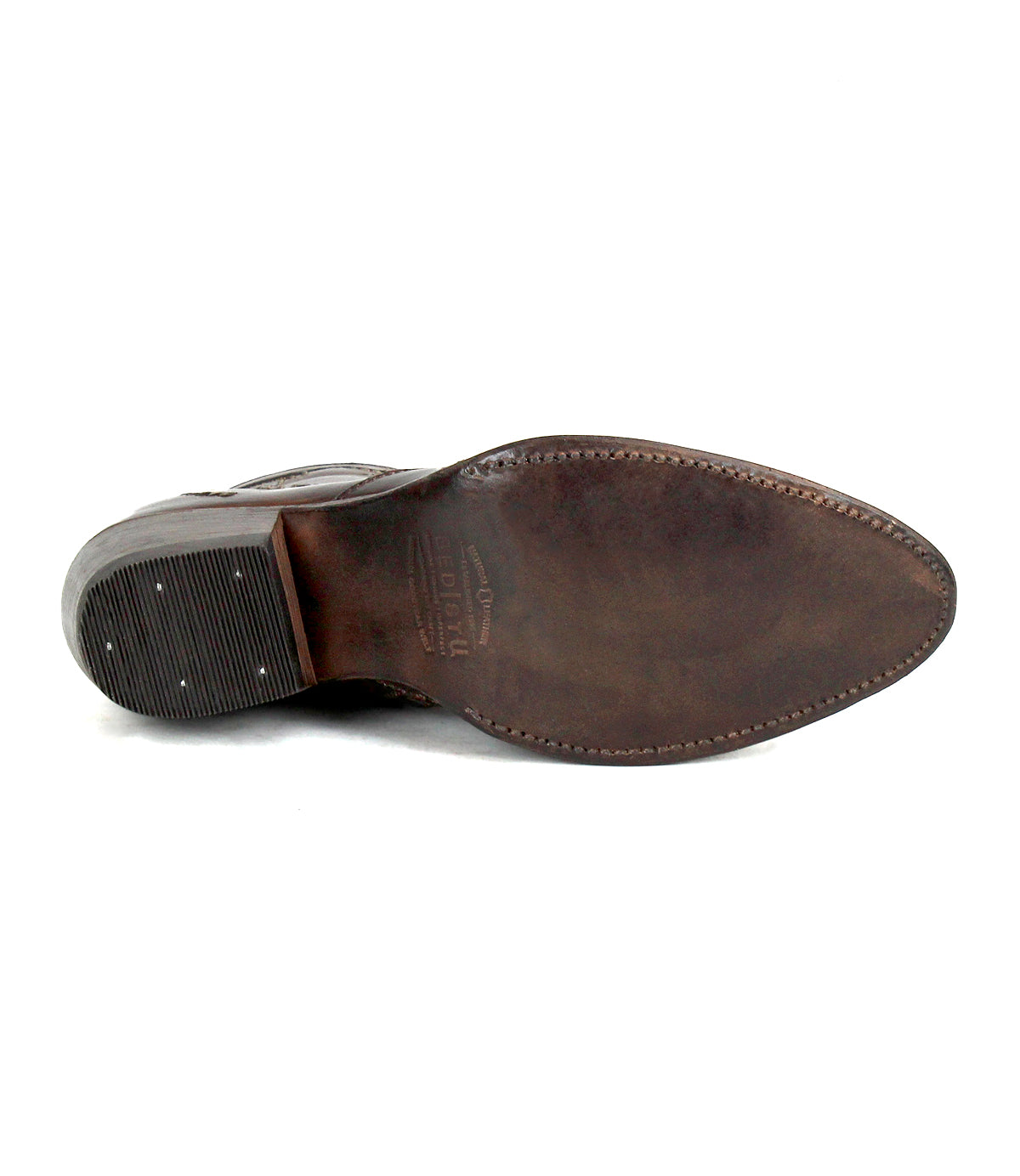 The Bed|Stü Laredoa brown leather dress shoe is pictured from the bottom, showcasing its sole, heel, and meticulous stitching—details that echo the artisanal craftsmanship of feminine cowboy boots.