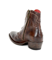 The Bed|Stü Laredoa is a brown leather ankle boot with a side zipper and low heel, featuring subtle western-inspired details, shown from the back and side on a white background.