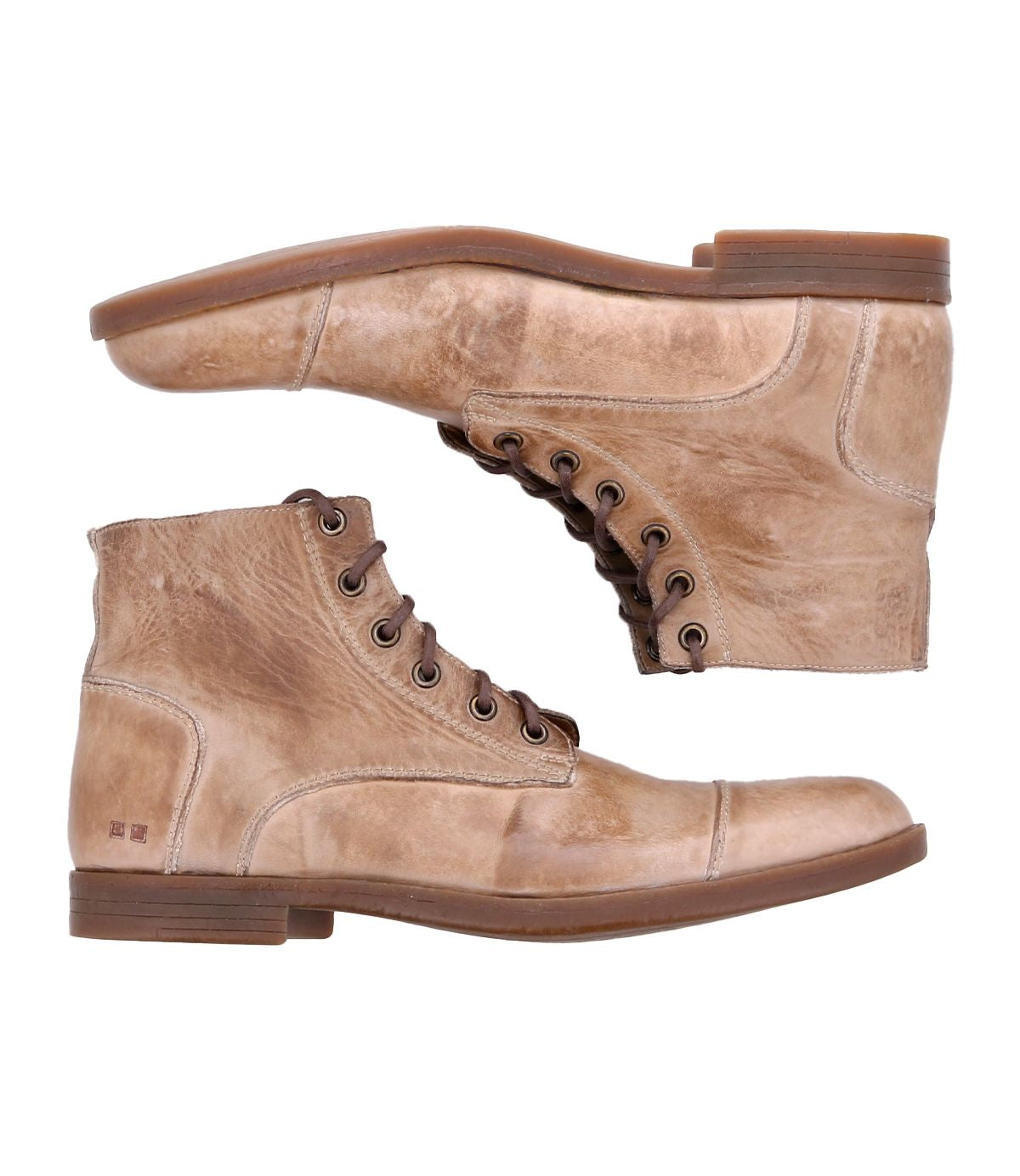 The Leonardo boots by Bed Stu are two tan leather lace-up boots with a distressed finish, positioned one above the other. These boots feature brown soles, visible stitching details, and comfortable insoles, complemented by a flexible rubber outsole for added comfort.