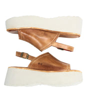 Bed Stu’s Library sandals feature brown leather uppers and white thick soles, blending ‘90s nostalgia. One image shows a top view, the other highlights the retro-styled side profile.