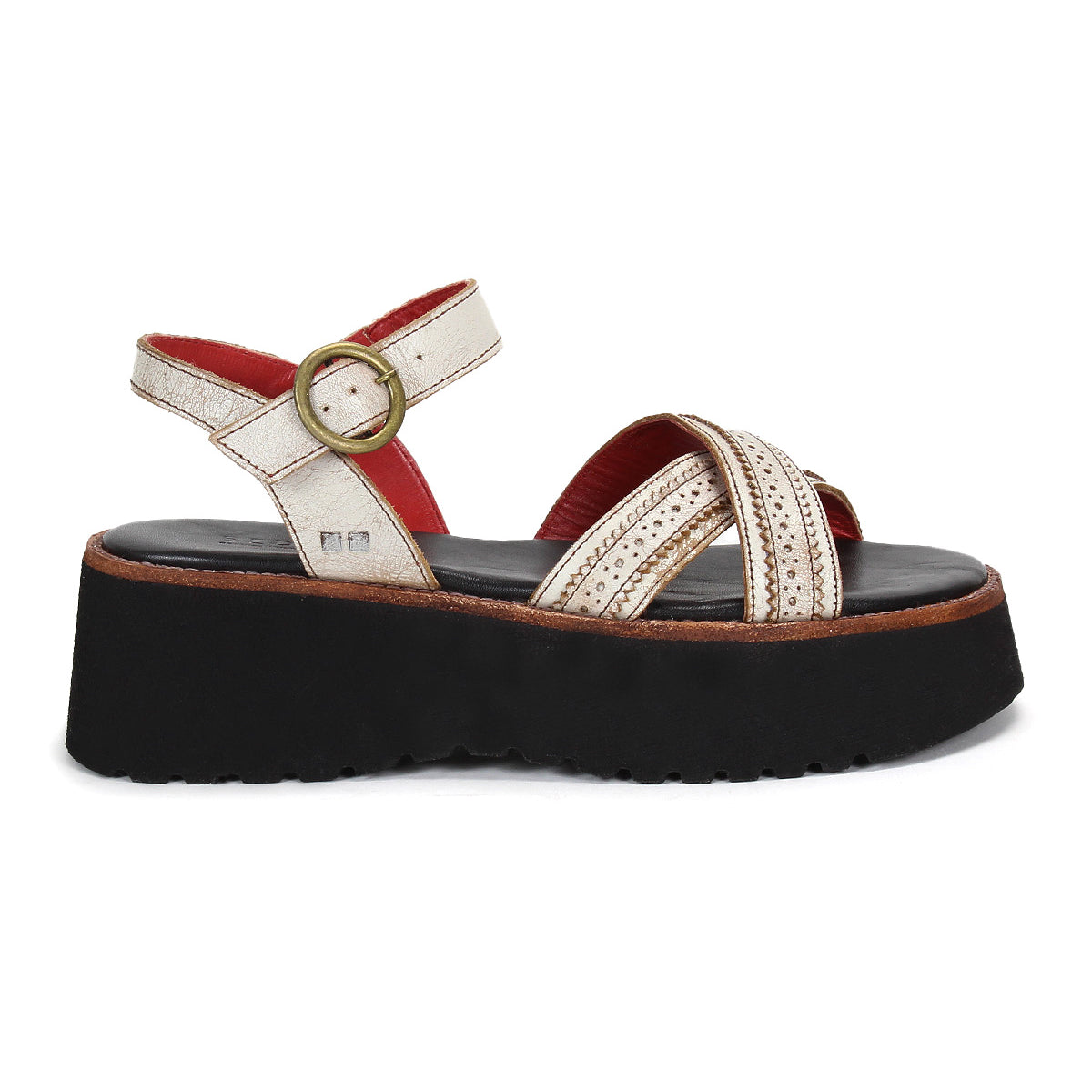 The Bed Stu Lift features a thick black platform sole, metallic gold crisscross straps, an adjustable ankle buckle for comfort, and a striking red inner lining.