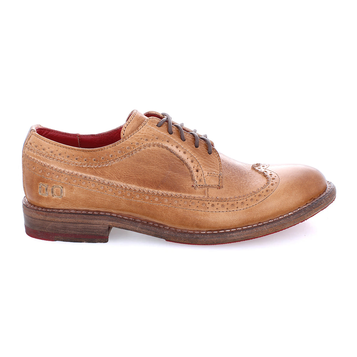 The Bed Stu Lita K II features a classic derby silhouette with brown leather, wingtip design, decorative perforations, and a bold red interior lining, offering a sophisticated look ideal for discerning footwear aficionados.