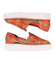 The Lizzie by Bed Stu are hand-woven leather sandals featuring orange and green straps alongside white platform huarache soles, displayed side by side.