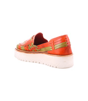 The Lizzie by Bed Stu features a hand-woven leather design in orange and green, with a thick white sole in the platform huarache style, viewed from the back.