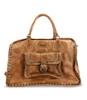 The Bed Stu Loaf is a brown leather handbag featuring dual handles, crafted from quality leather. It includes a front pocket with buckle and stud accents, making it perfect as a chic carry-on.