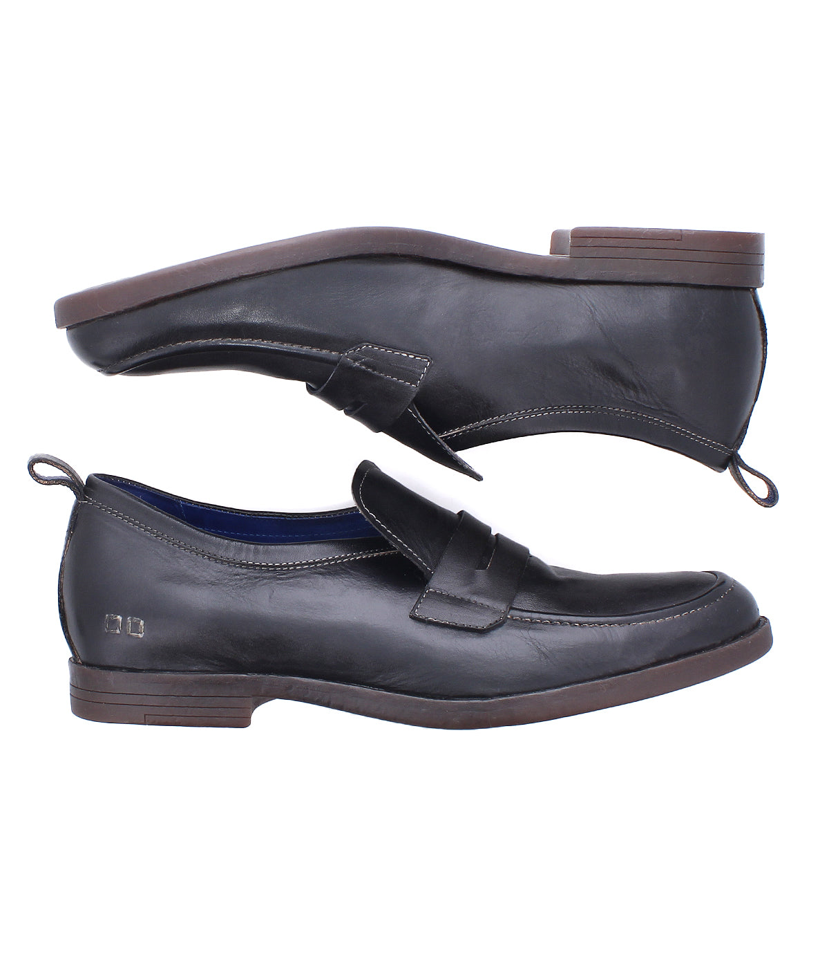 Two black Lumaro penny loafers by Bed|Stü, crafted from supple distressed leather with low brown heels, are displayed side by side—one upright and one sideways—to showcase different angles and the flexible loafer design.