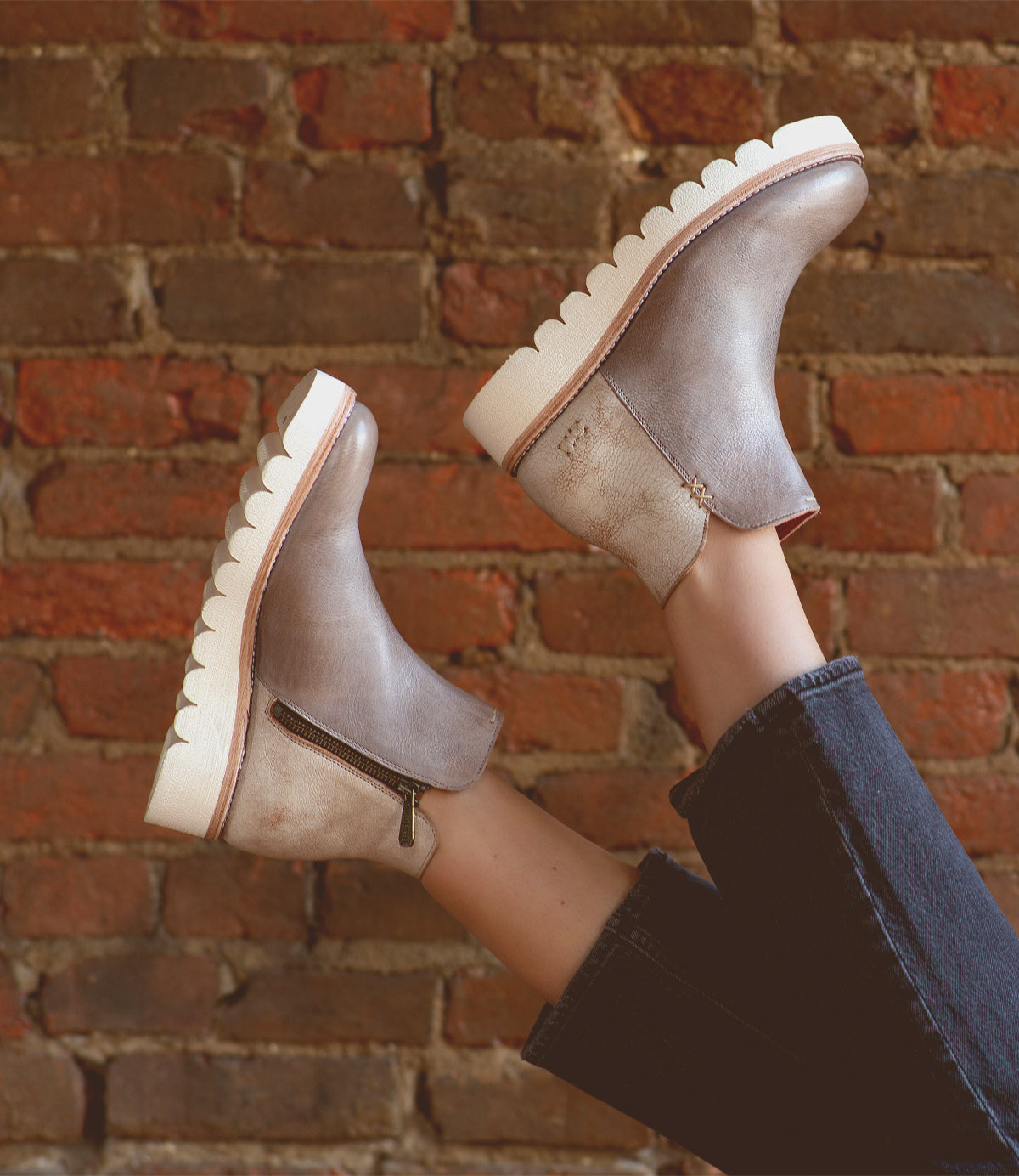A versatile woman's legs in a pair of Bed Stu Lydyi ankle boots against a brick wall.