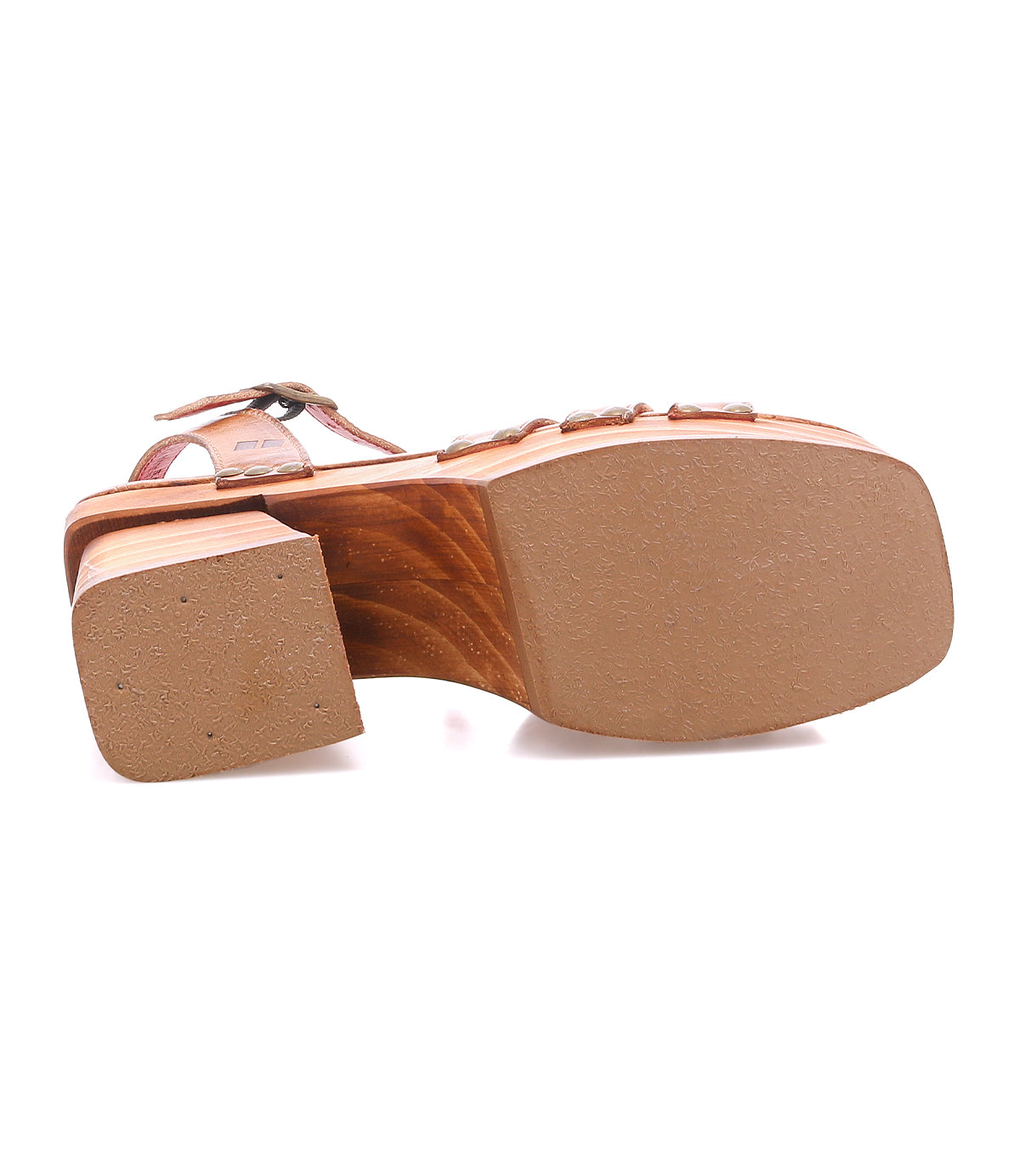 The image displays the Bed Stu Lyxon sandal’s bottom view, highlighting its thick, flat sole, low chunky heel with a wooden texture, tan rubber outsole, and open-toe design for added sturdiness.