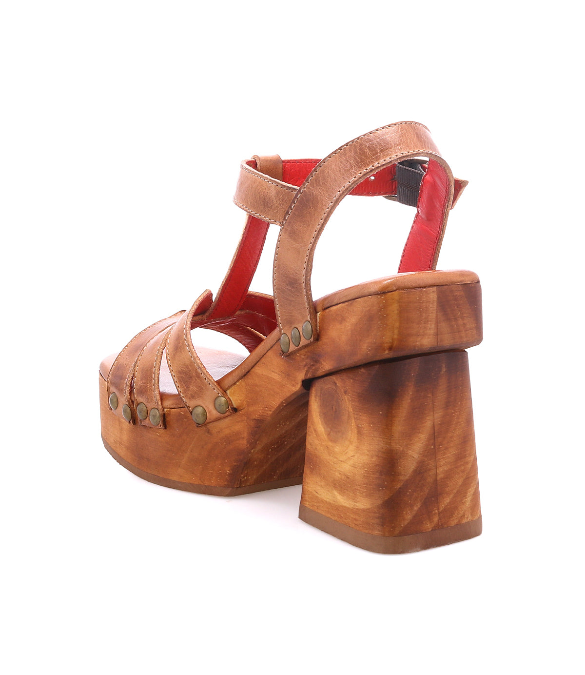 The Bed Stu Lyxon is a brown wooden platform sandal with leather t-strap and open-toe design, thick heel, metal rivet accents, and red lining, shown against a white background.