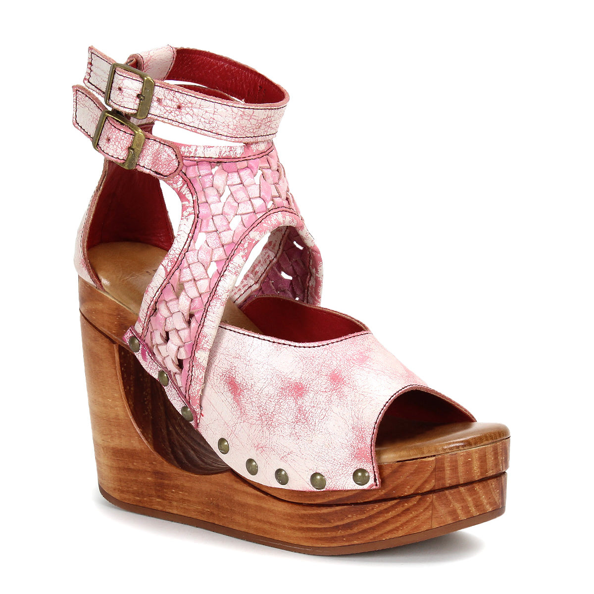 The Bed Stu Magic is a pink open-toe sandal featuring a woven leather upper, adjustable ankle strap, metal studs, and a platform wooden wedge heel.