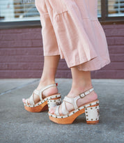 Woman standing on a sidewalk wearing pink pants and comfortable, Bed Stu stud-detailed sandals.