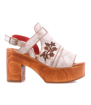 The Bed Stu Melodramatic is a platform sandal with a chunky leather heel, beige embroidered leather upper with floral designs, and an adjustable ankle strap.