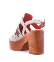 The Bed Stu Melodramatic is a platform sandal with a chunky leather heel, silver straps, floral embroidery, and a red interior lining, shown from the back.