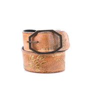 The Bed Stu Mohawk women's belt is crafted from brown distressed leather with floral embroidery and a bold geometric metal buckle, shown rolled up on a white background.