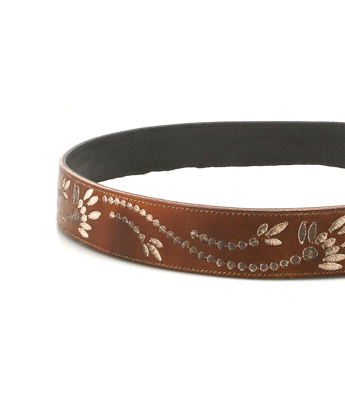 The Bed Stu Mohawk is a women’s belt made from brown distressed leather, featuring silver floral and leaf embossing, shown in a circular layout on a white background.