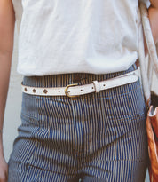 A person wearing pinstripe pants with a white Bed Stu premium leather belt.