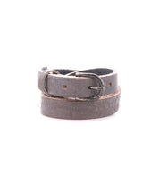 The Bed Stu Monae is a dark brown leather belt with a metal buckle, ideal for a boho touch. Shown coiled on a white background.